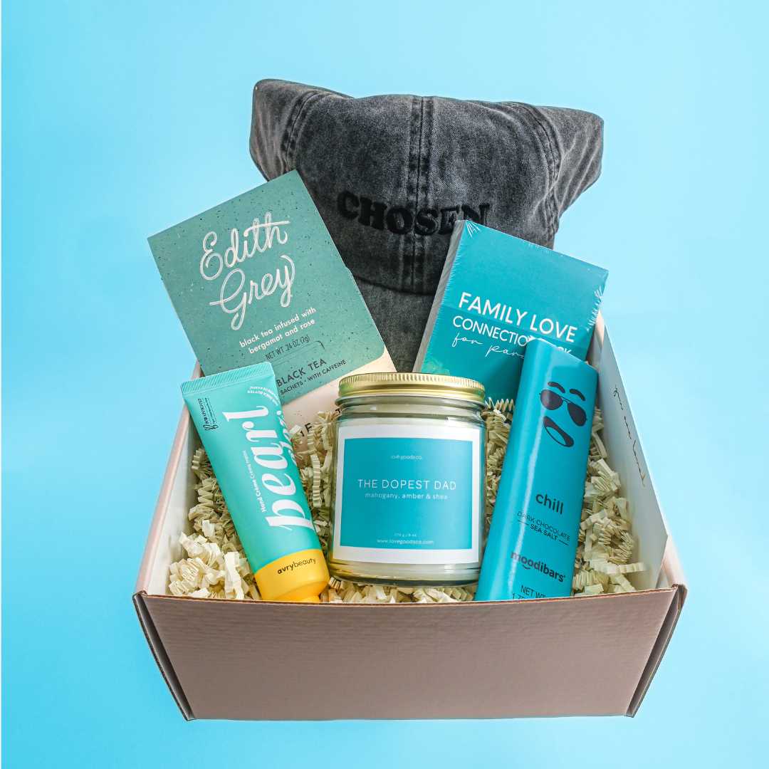 Gift box with a candle, books, and a hat on a blue background